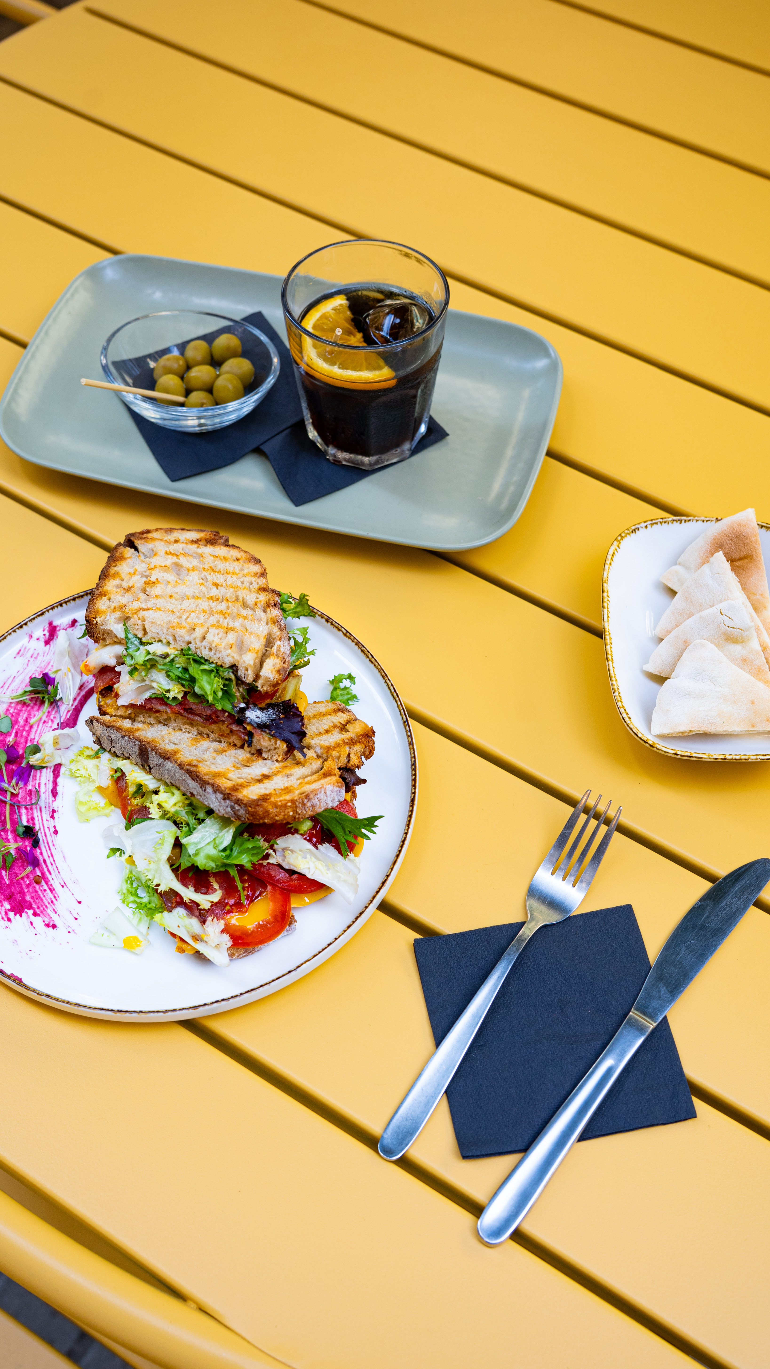 Sándwich y bebidas sobre mesa amarilla en Afecte Brunch